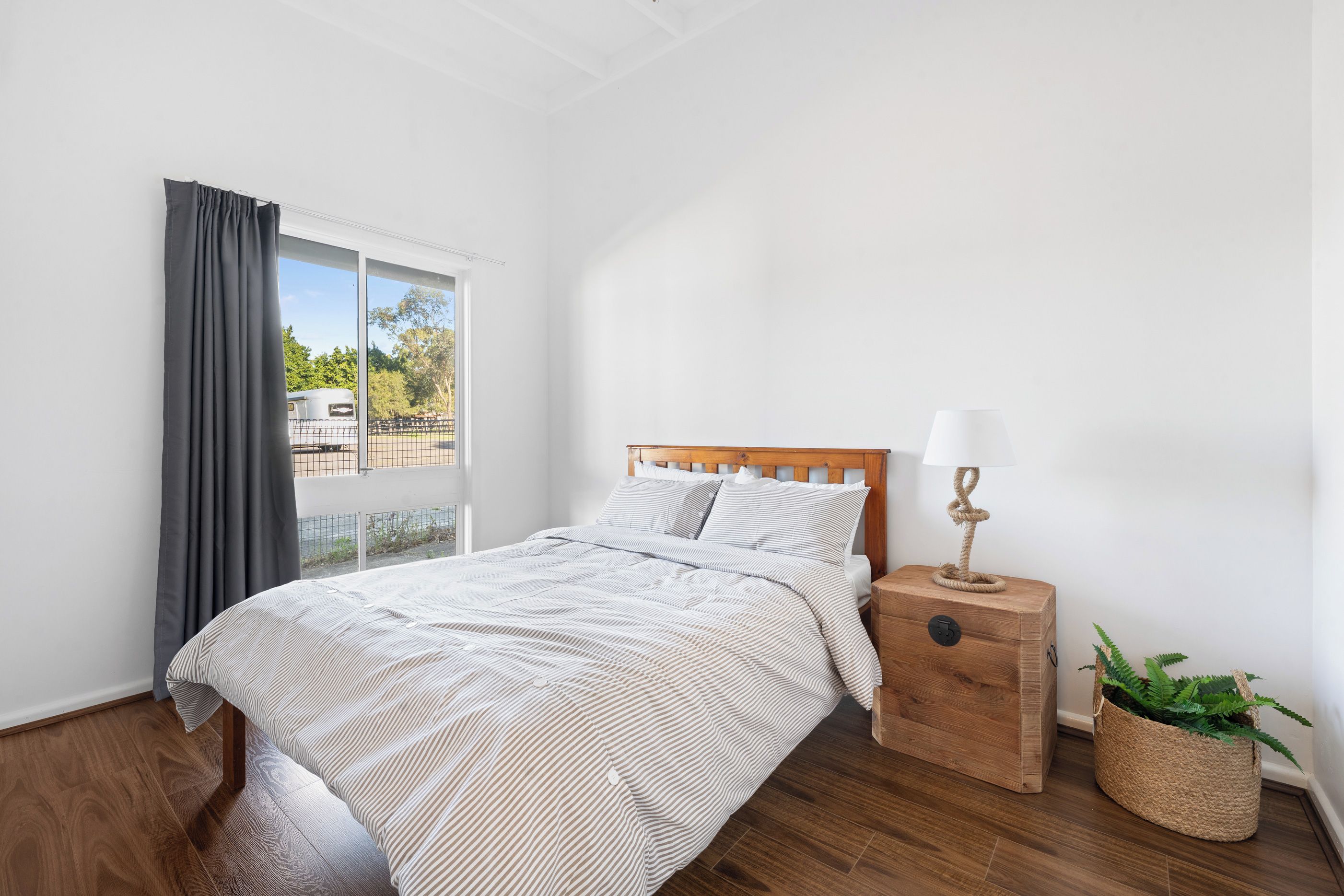 A bedroom with a bed, a nightstand, a lamp, and a window with curtains.