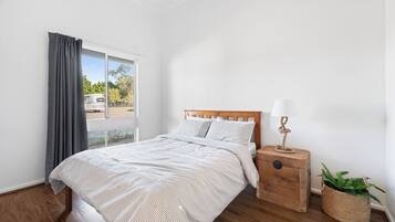 A bedroom with a bed, a nightstand, a lamp, and a window with curtains.