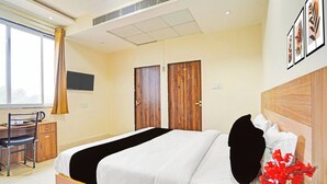Ein Hotelzimmer mit Bett, Schreibtisch, Stuhl, Fernseher und Fenster.