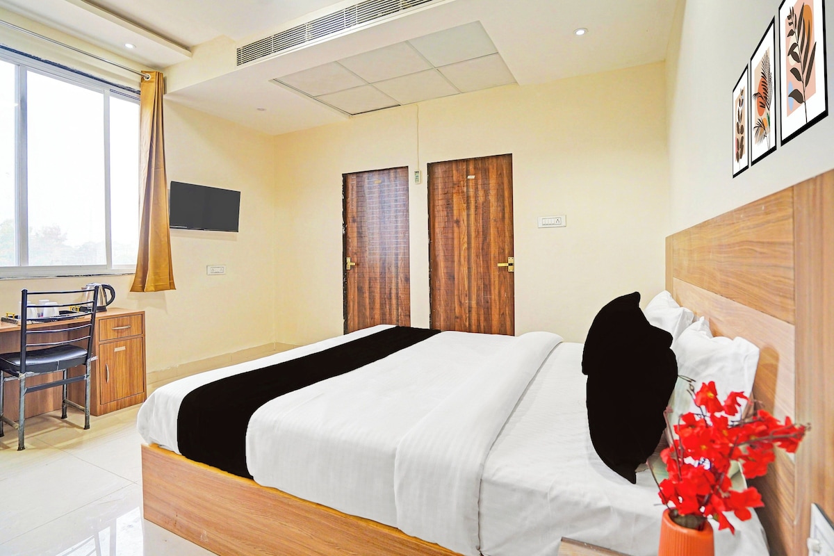 Ein Hotelzimmer mit Bett, Schreibtisch, Stuhl, Fernseher und Fenster.