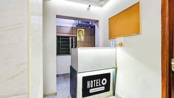 En hotelindgang med reception, overvågningskamera og et skilt på væggen.
