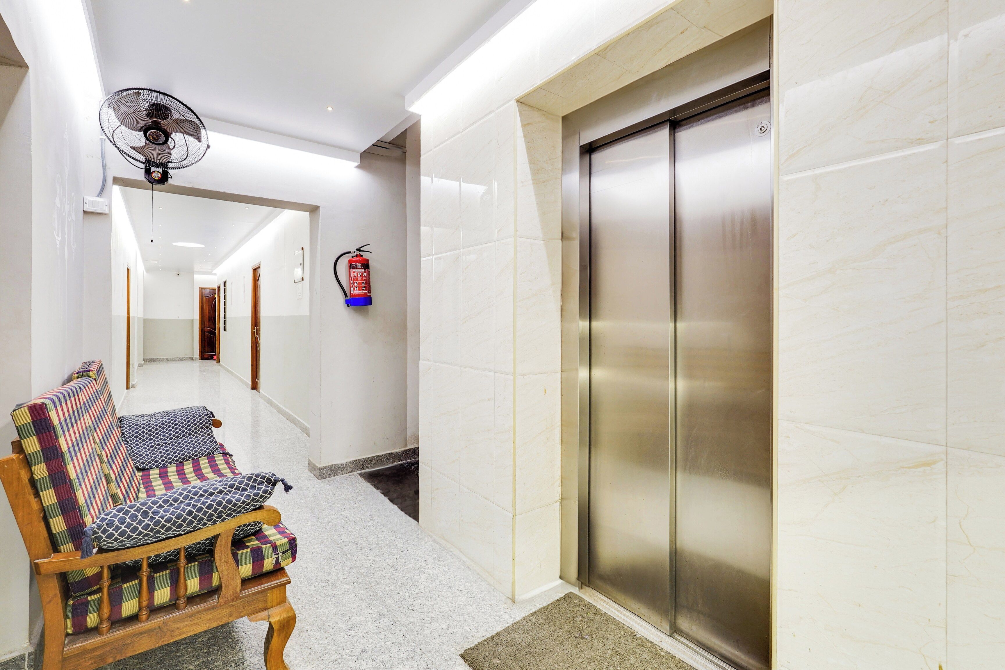 A hotel hallway with a wooden bench, a fire extinguisher, and an elevator.