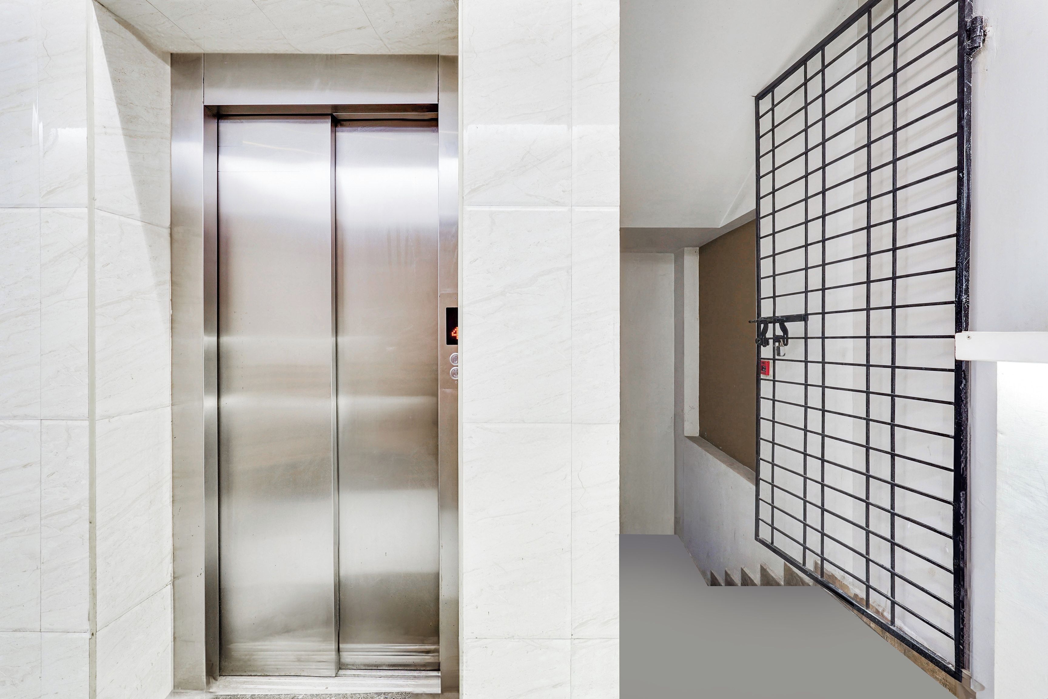 En elevator med metalfinish og et kontrolpanel med knapper.