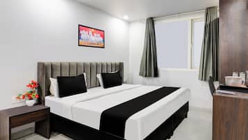 Una habitación de hotel moderna con cama, mesita de noche y ventana con cortinas.