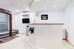 A reception area with a reception desk, a mounted television, and a sign indicating company service.