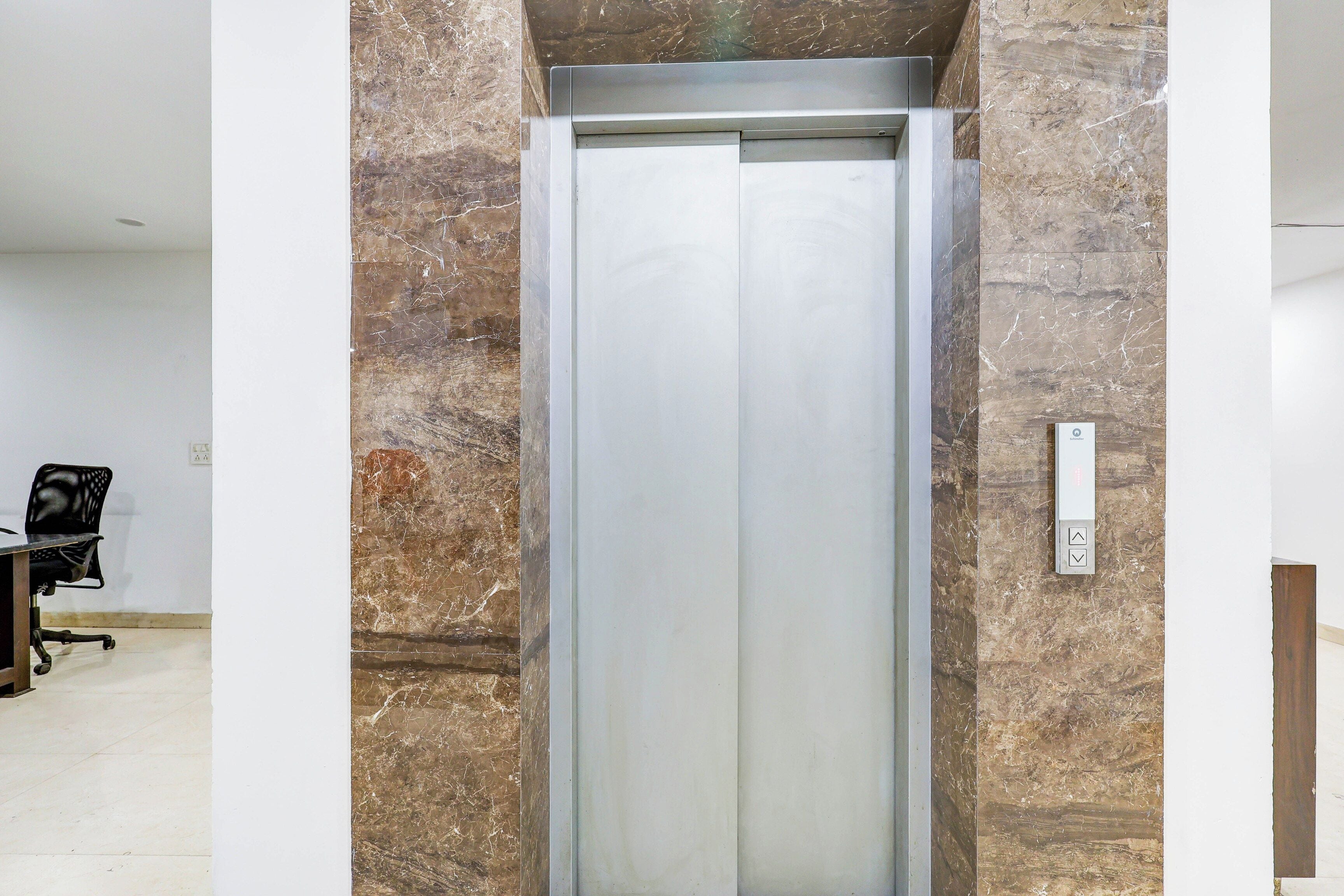 An elevator in a modern building with marble walls.