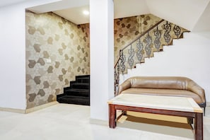 A staircase with a geometric patterned wall, a leather sofa, and a wooden table.