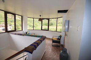 Una habitación con un largo banco a lo largo de la pared, una pequeña mesa con una silla y un cilindro de gas.