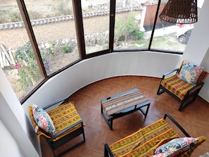 Una habitación con pared curva y ventanas amplias, que incluye dos sillones con cojines estampados y una mesita.