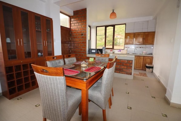 Un comedor con una mesa y sillas de madera, un muro de ladrillo y una cocina con armarios de madera.
