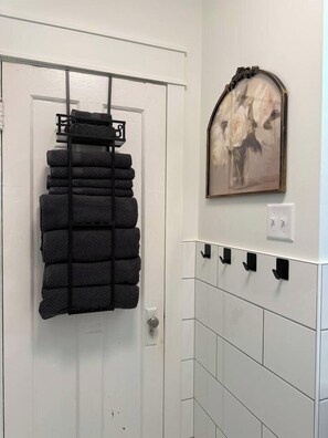 A bathroom with a towel rack, a wall-mounted picture, and a tiled wall.