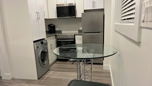 Een moderne keuken met roestvrijstalen apparatuur, een glazen tafel en een ingebouwde wasmachine.