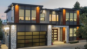 Een modern herenhuis met garage, grote ramen en een gevel van natuursteen.