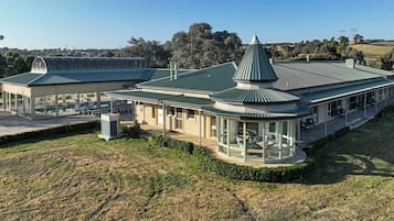 A modern building with a curved roof, large windows, and outdoor seating areas.