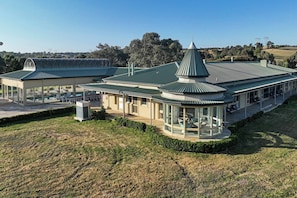 A modern building with a curved roof, large windows, and outdoor seating areas.