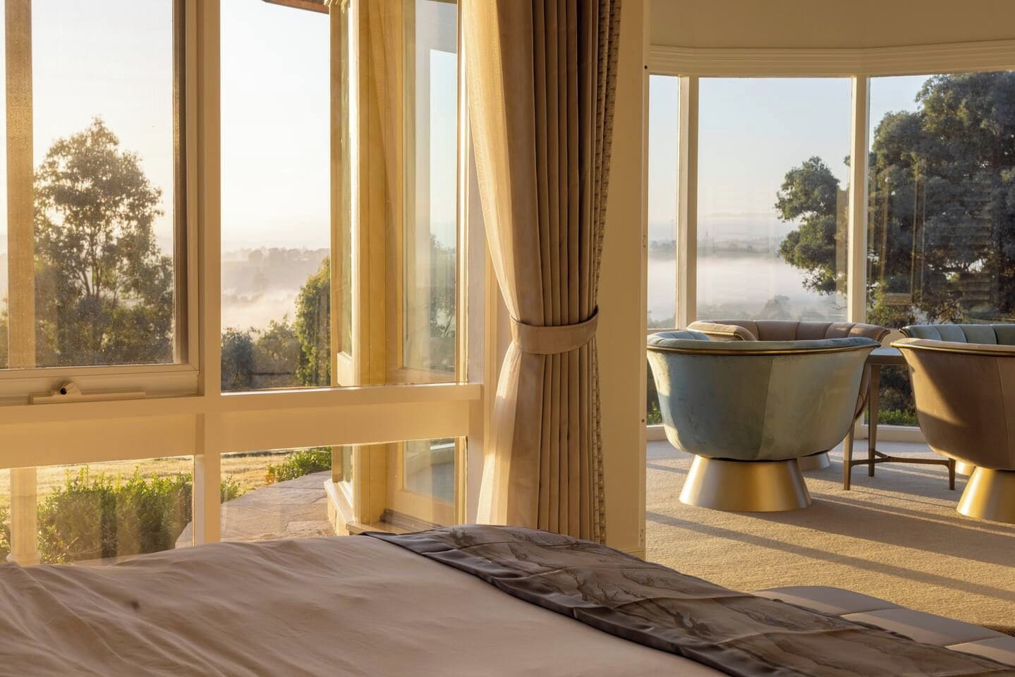 A bedroom with a large window, a bed, and two vintage-style bathtubs.