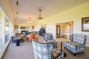 A spacious living room with a sofa, armchairs, a coffee table, and a television.