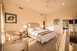 Une chambre d’hôtel équipée d’un lit, de tables de chevet, d’une chaise, d’un bureau et d’un ventilateur de plafond.