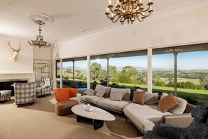 Un salón amplio con un ventanal grande que ofrece vistas panorámicas, una chimenea y muebles modernos.