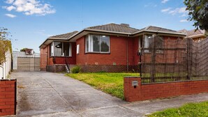 A two-story brick house with a front yard, a metal gate, and a wooden fence. - Spacious 4-bed House With Garden in Glenroy (Melbourne)