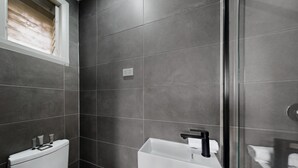 A modern bathroom with a toilet, sink, and shower area. - Spacious 4-bed House With Garden in Glenroy (Melbourne)