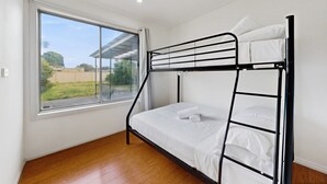 A bunk bed in a room with a large window, wooden flooring, and white walls. - Spacious 4-bed House With Garden in Glenroy (Melbourne)