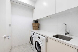 Ein kleiner Waschbereich mit Waschmaschine, Spüle und einem Weidenkorb auf einer Arbeitsplatte.