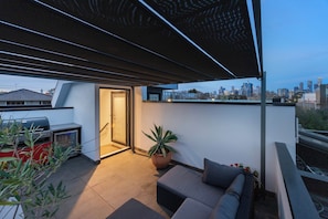 An outdoor patio with a grill, seating, and a city view. - The Port Residence Luxury Port Melbourne Townhouse (Port Melbourne)