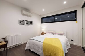 Ein Schlafzimmer mit einem Bett, einem Heizkörper, einem Fenster und drei gerahmten Bildern an der Wand.