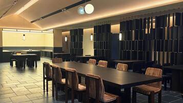 Un salón de conferencias con una larga mesa y sillas, una lámpara moderna y un papel tapiz con diseño.