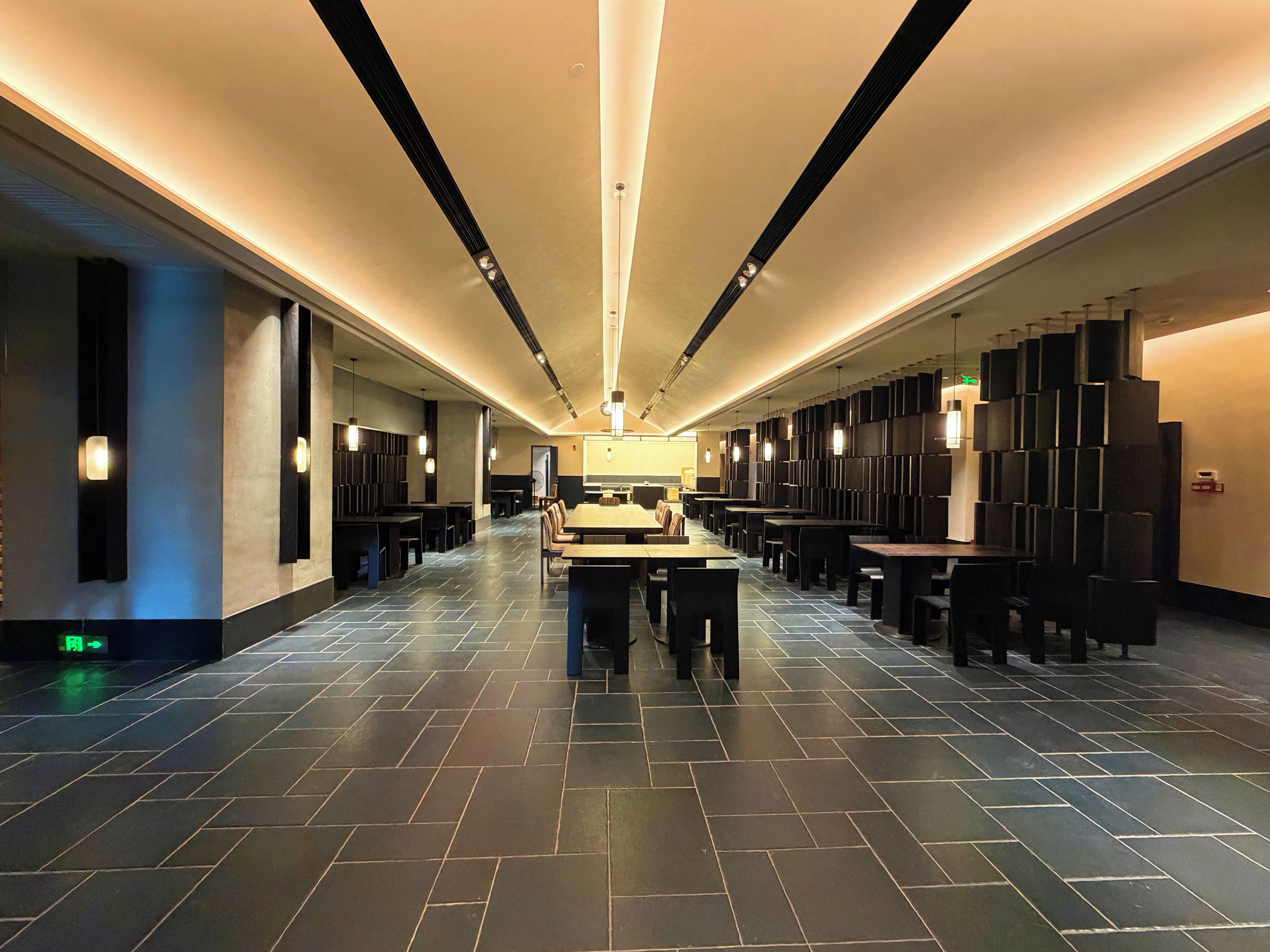 A spacious hotel lobby with a long reception desk, multiple seating areas, and a modern design.