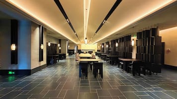 A spacious hotel lobby with a long reception desk, multiple seating areas, and a modern design.