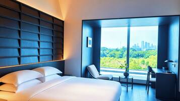 A modern hotel room with a large bed, a desk, and a view of a cityscape.