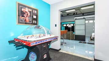 A room with a foosball table, a framed photo on the wall, and a bar area with stools.