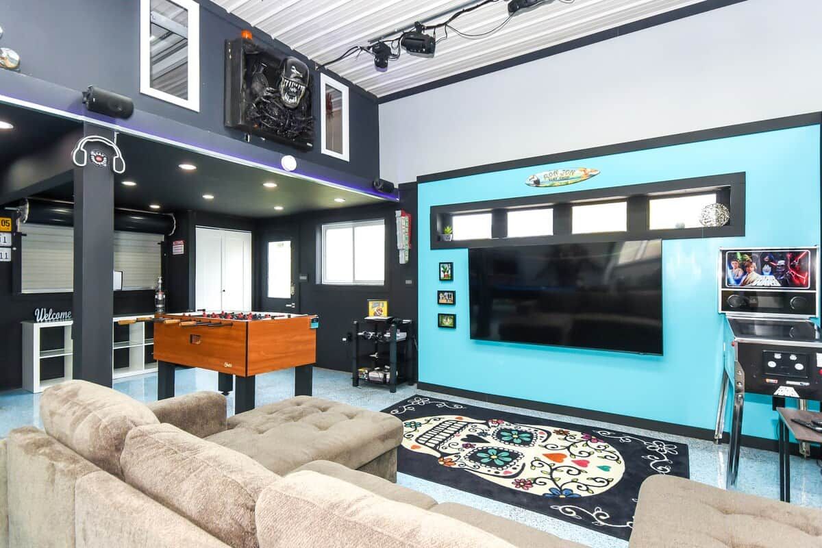 A room with a foosball table, a large flat-screen TV, and a patterned rug.