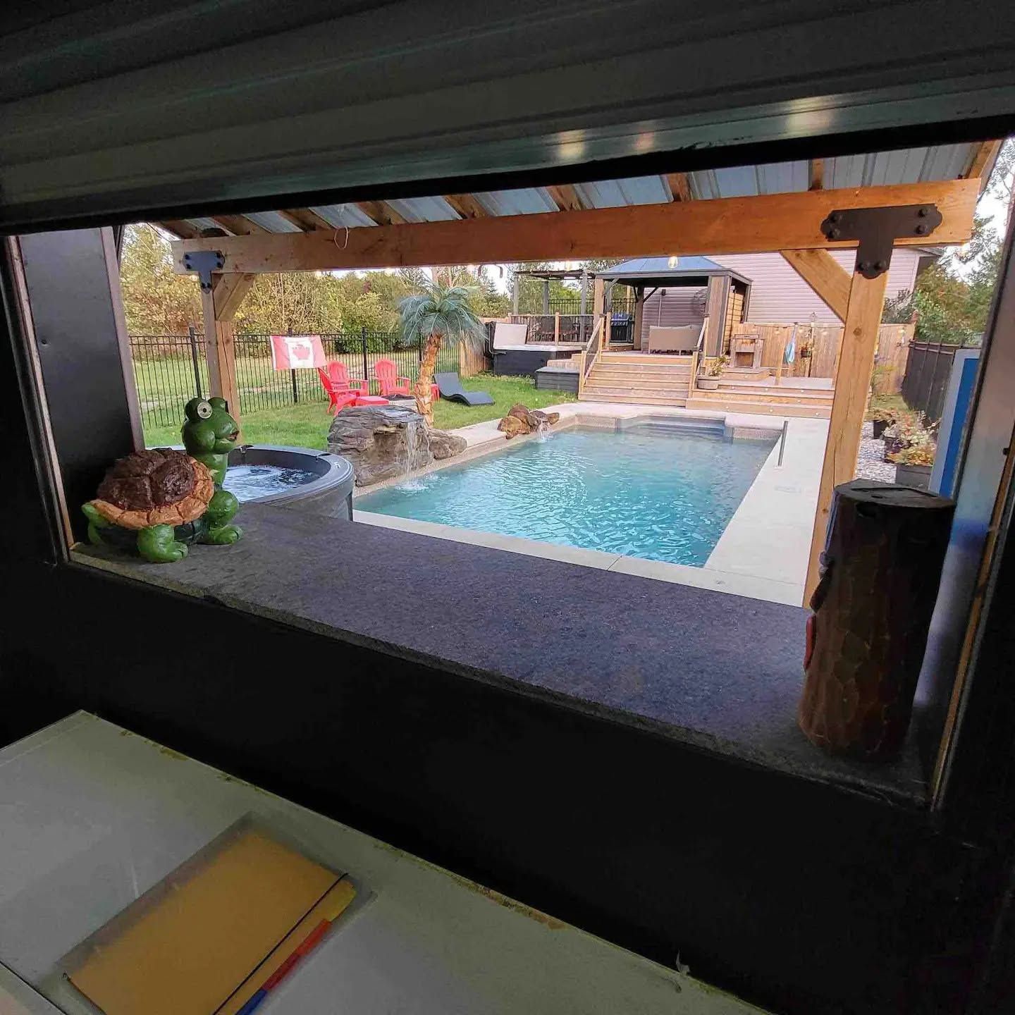 A view of a backyard with a swimming pool, a hot tub, and a wooden deck.