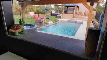 A view of a backyard with a swimming pool, a hot tub, and a wooden deck.