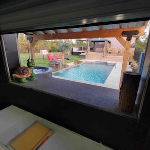 A view of a backyard with a swimming pool, a hot tub, and a wooden deck.