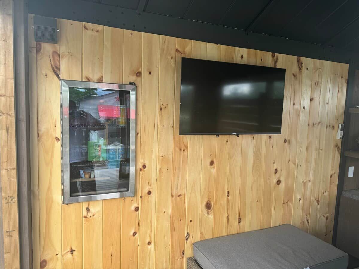A room with a wooden wall, a window, and a flat-screen TV.