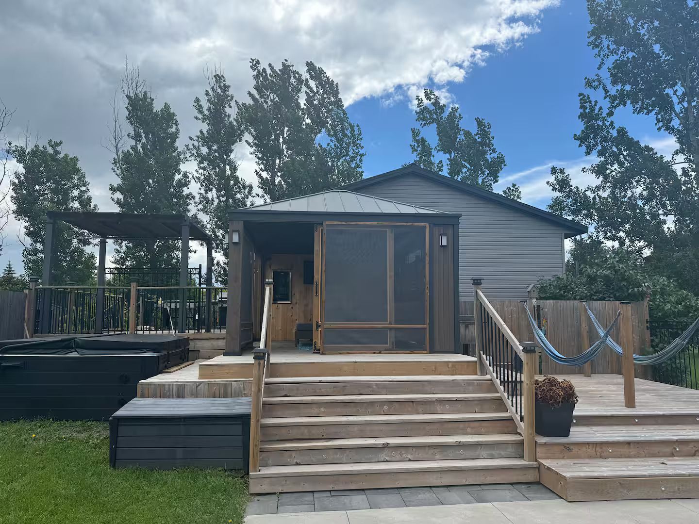 A house with a wooden deck, a covered porch, and a fenced backyard.