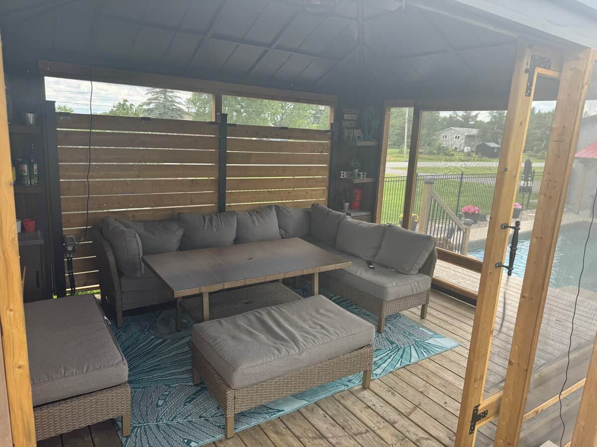 Een overdekt terras met een hoekbank, een tafel en een bank.