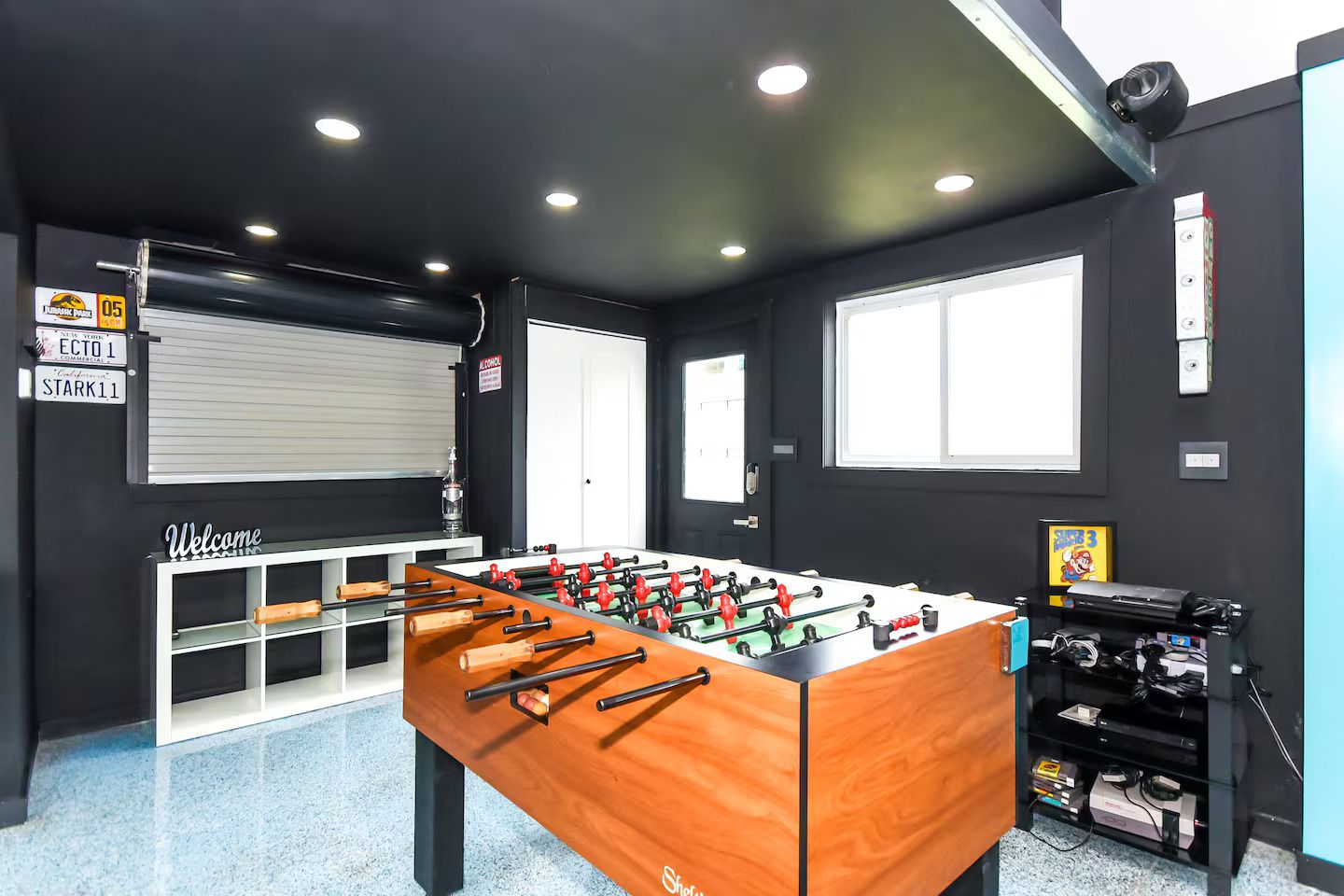 A room with a foosball table, a window, and a door.