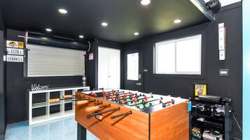 A room with a foosball table, a window, and a door.