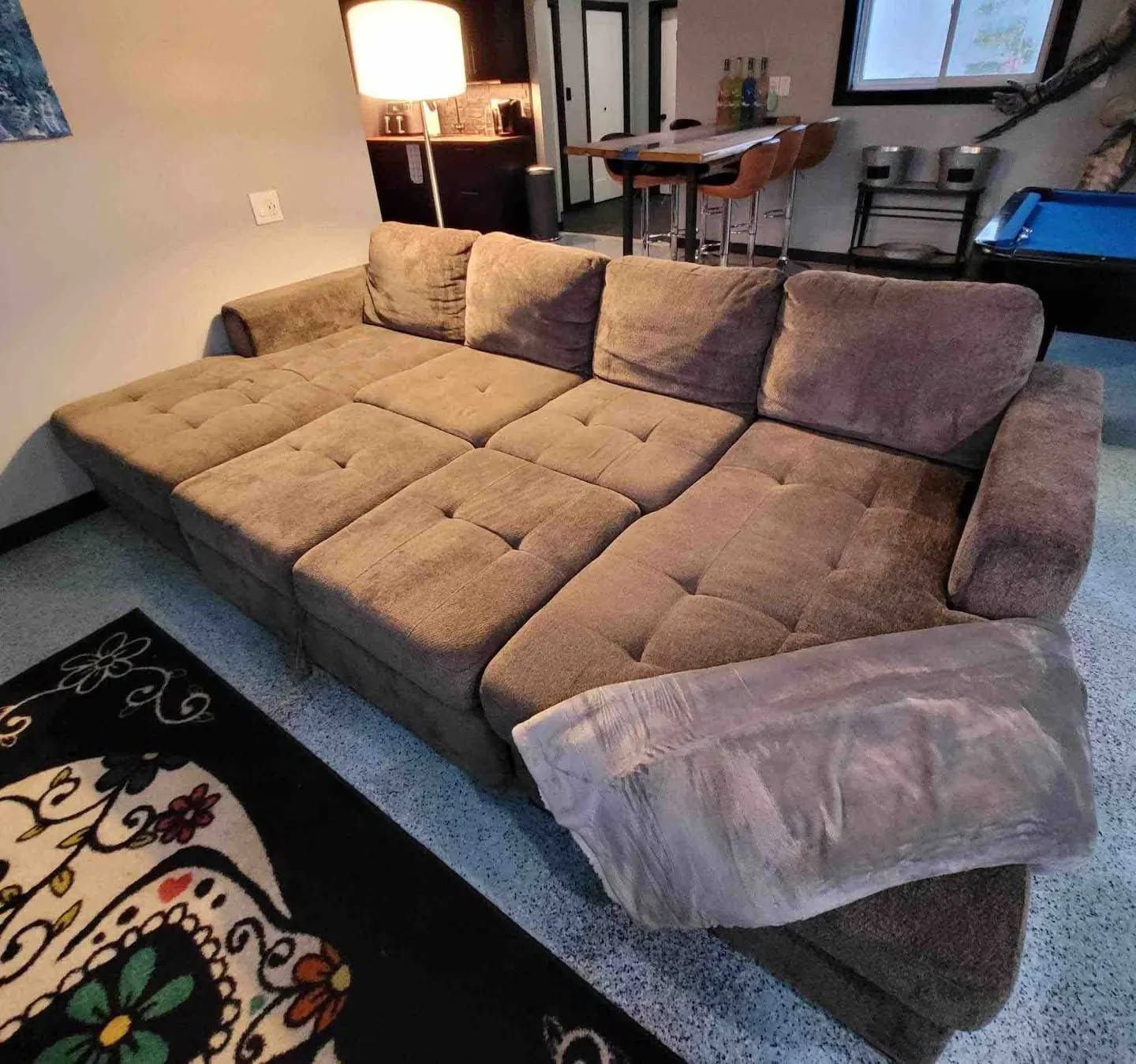 Ein Ecksofa in einem Wohnzimmer mit Couchtisch, Lampe und einem Essbereich im Hintergrund.