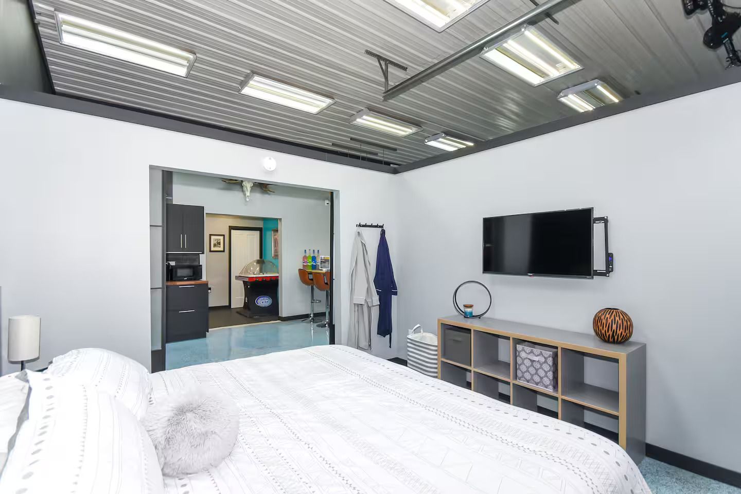 A hotel room with a bed, a TV, a minibar, and a bathroom visible through an open door.