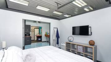 A hotel room with a bed, a TV, a minibar, and a bathroom visible through an open door.