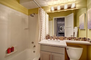 A bathroom with a bathtub, a shower, a sink with a mirror, and a toilet. - Elektra (Seattle)