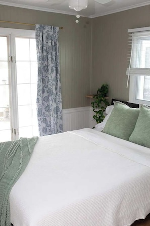 Un dormitorio con cama, cortinas, una ventana y una planta.