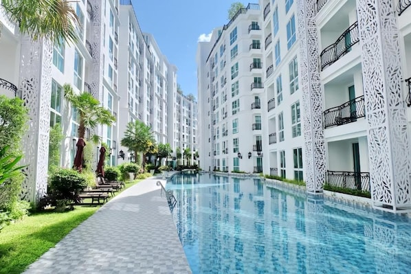 Ein Schwimmbecken, umgeben von mehrstöckigen Wohnhäusern mit Balkonen und Außenbereichen zum Sitzen.