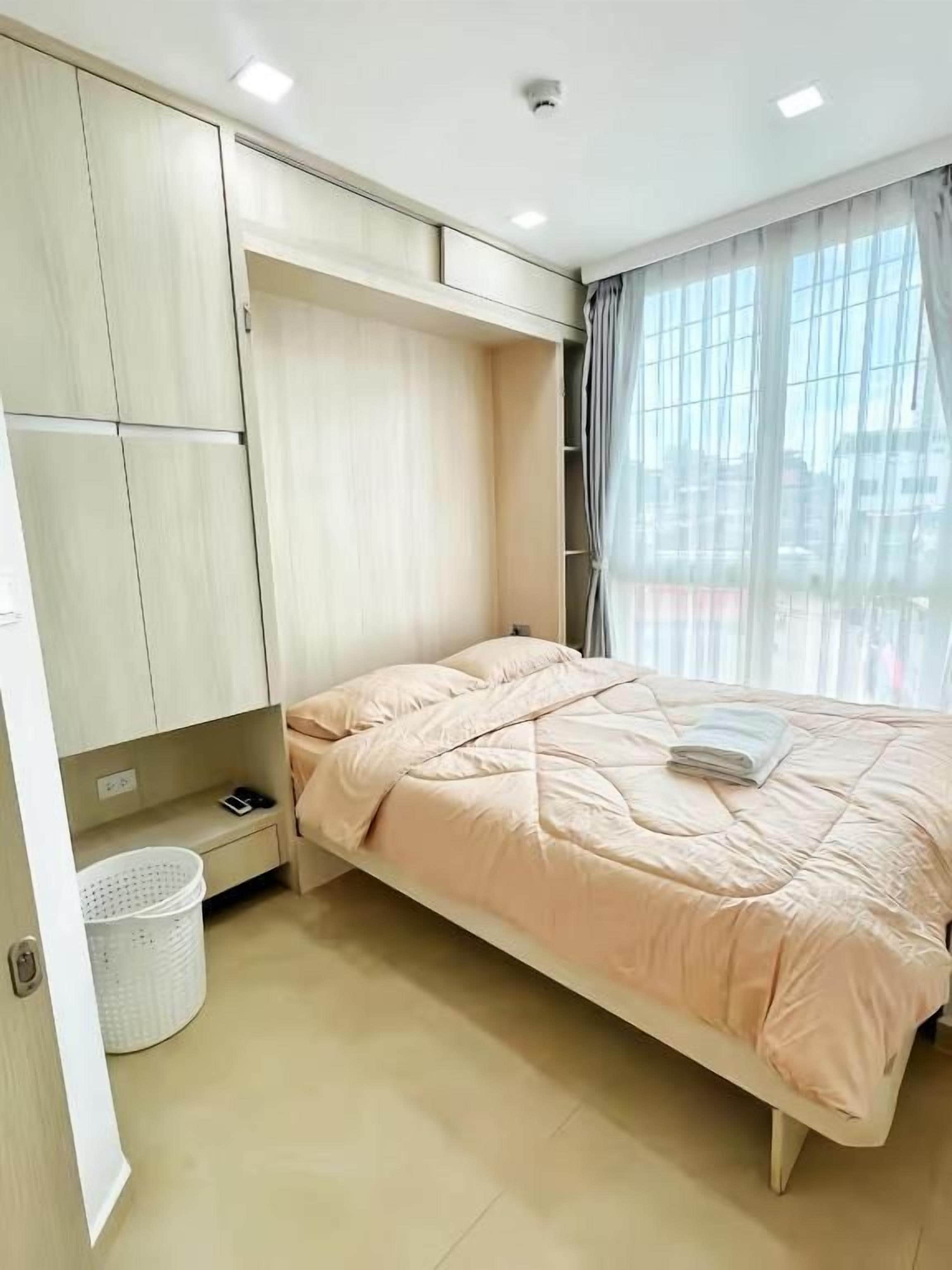 A bedroom with a bed, a wardrobe, a window with curtains, and a ceiling light.